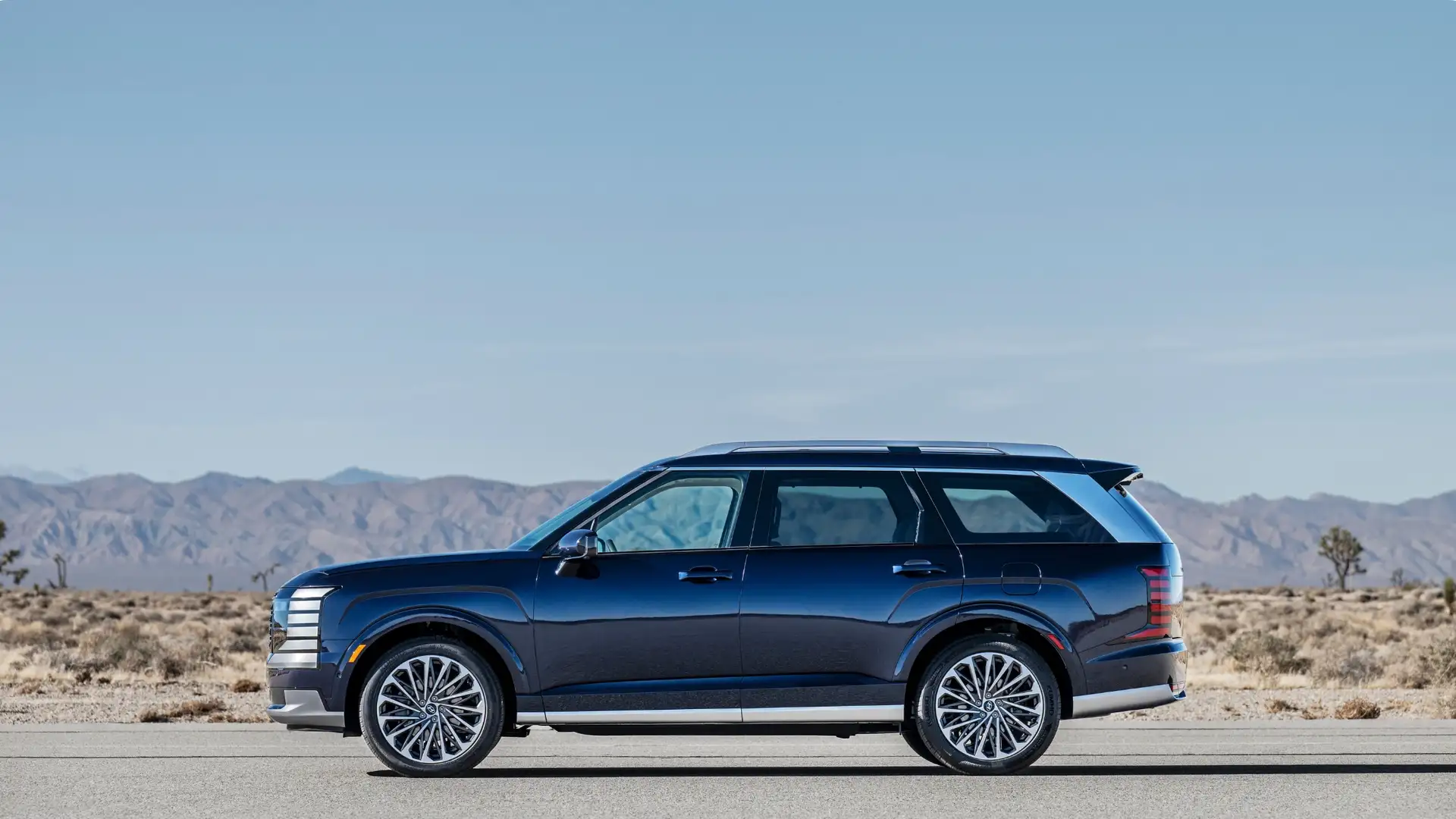 2026 Hyundai Palisade side profile in deep blue with chrome accents parked in a desert landscape.