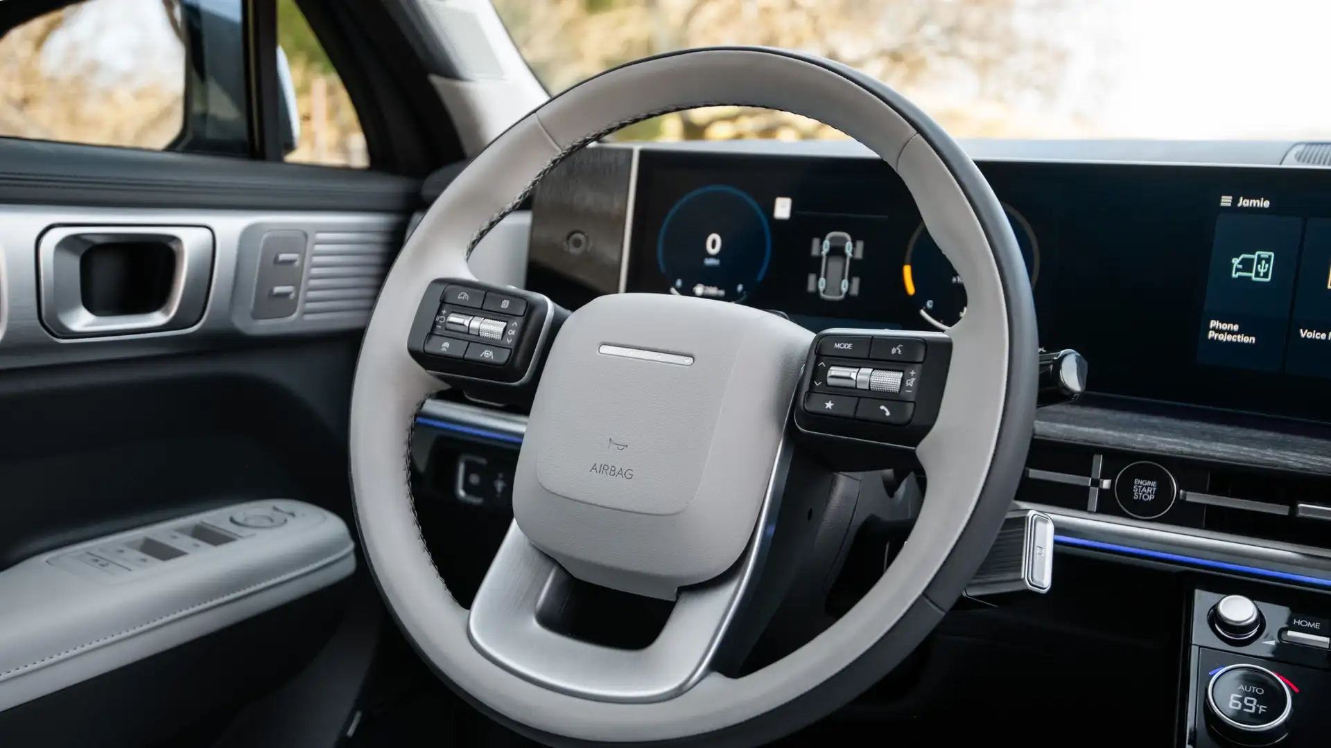 Interior cockpit of a 2026 Hyundai Santa Fe featuring a modern steering wheel, dual-screen display, and premium metallic trim.