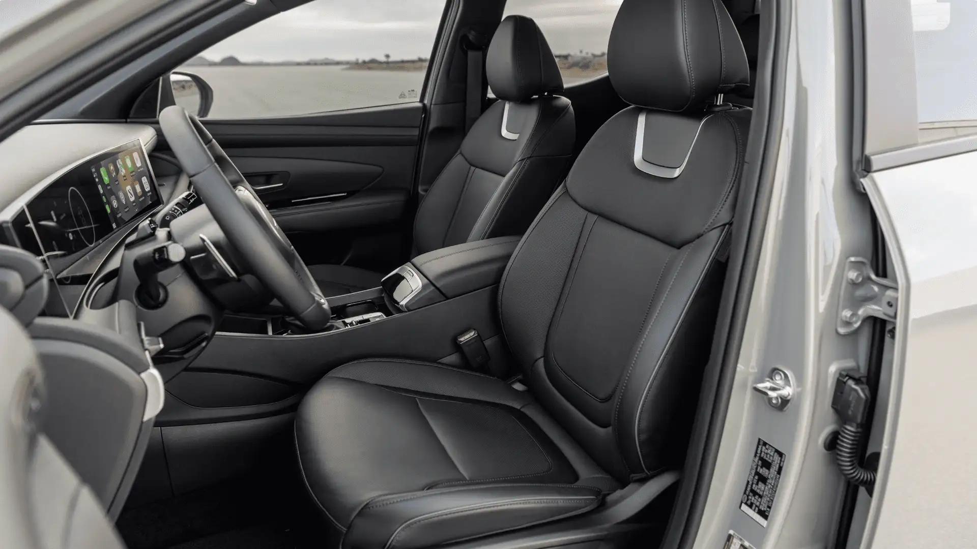 2026 Hyundai Santa Cruz front seats in black upholstery with open driver door and premium interior detailing.