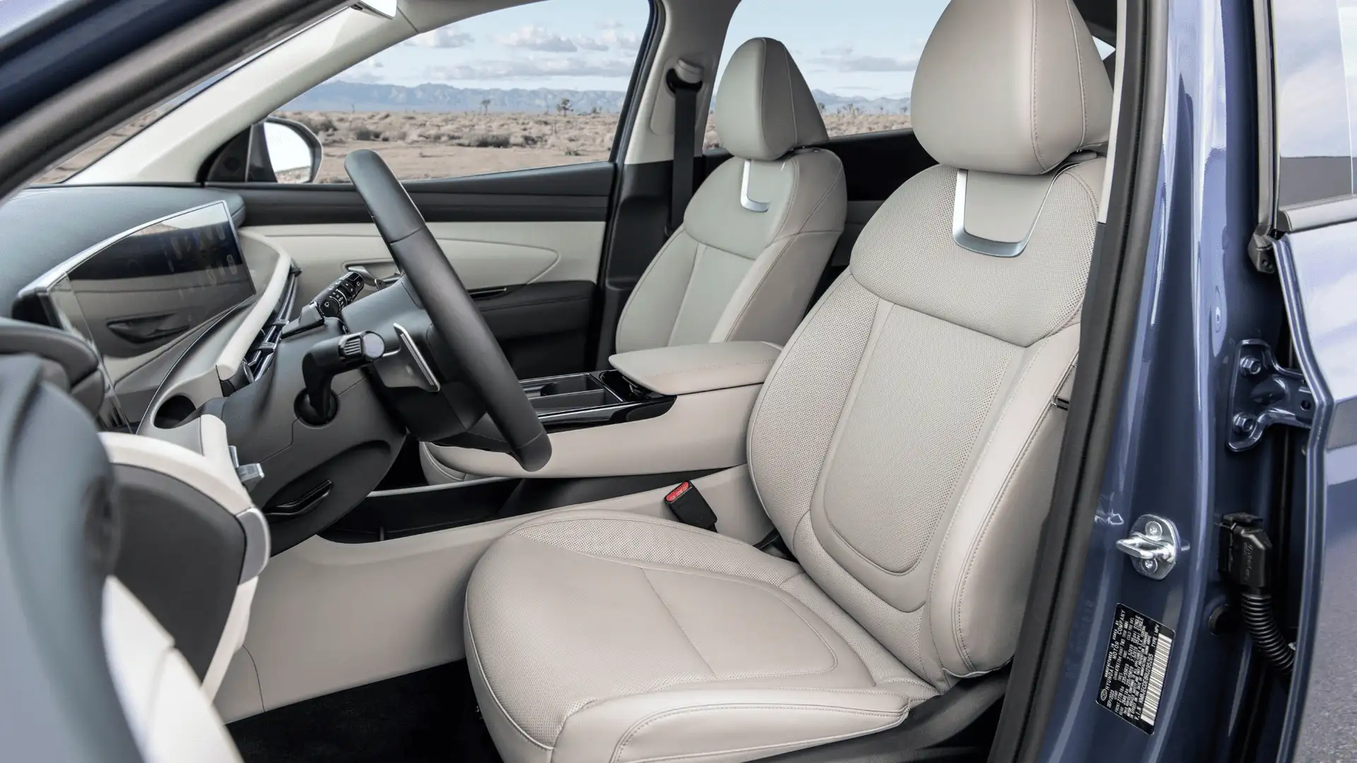 2026 Hyundai Tucson interior front seats with light upholstery, modern dashboard, and panoramic cabin layout.