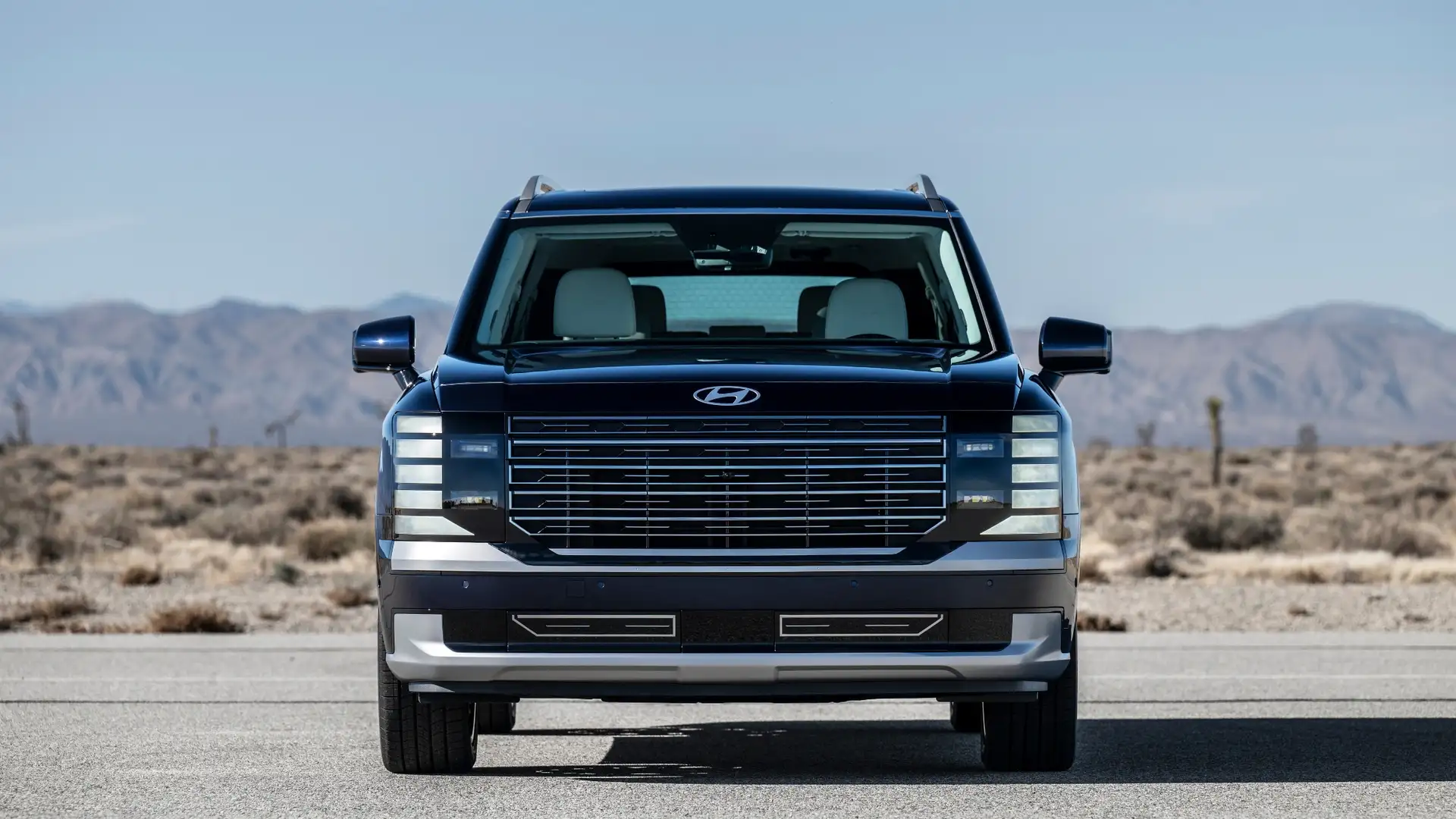 2026 Hyundai Palisade front view showcasing bold grille design parked on open highway.