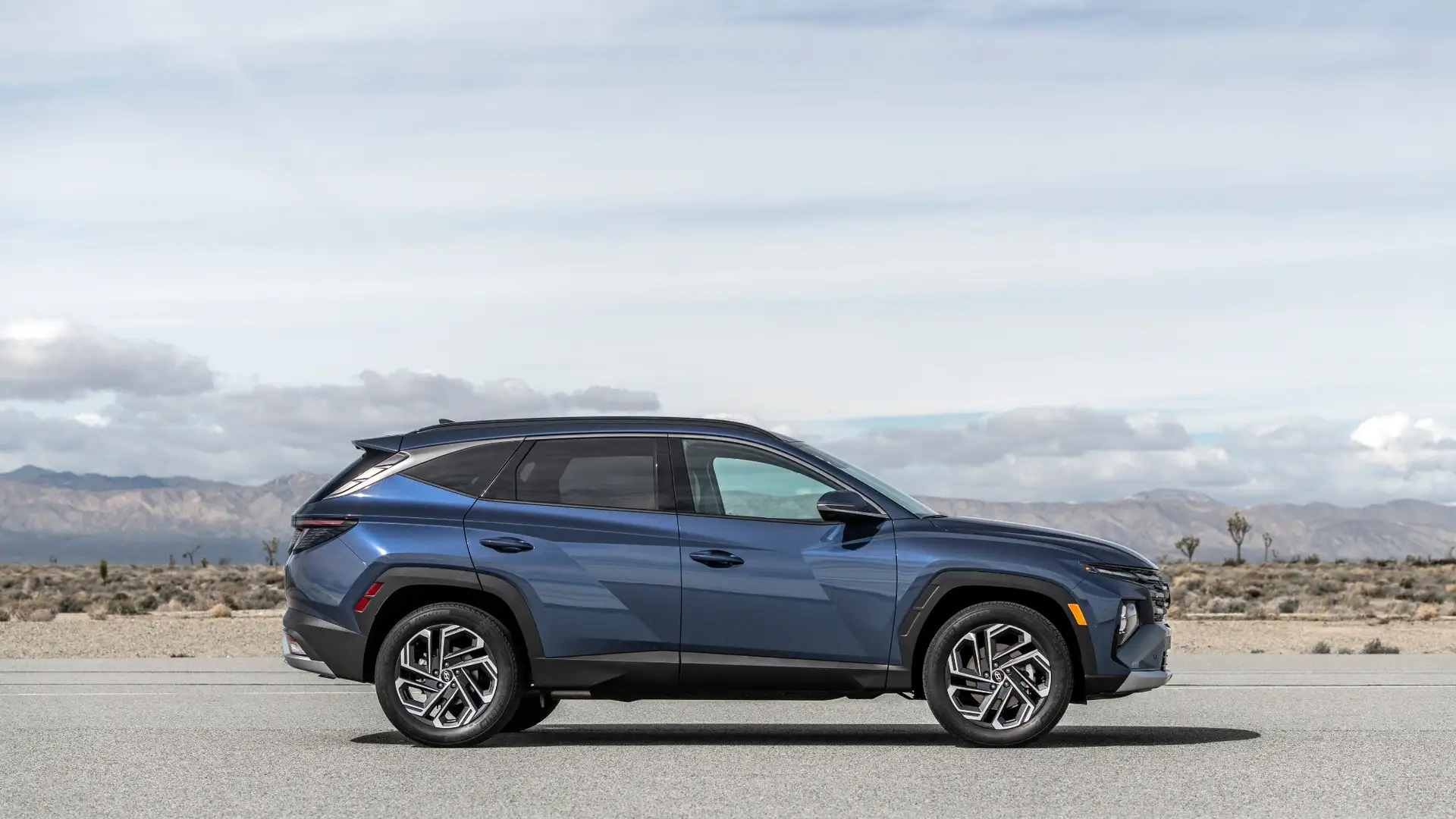 2026 Hyundai Tucson side profile driving on open road showing bold body lines and alloy wheels today.