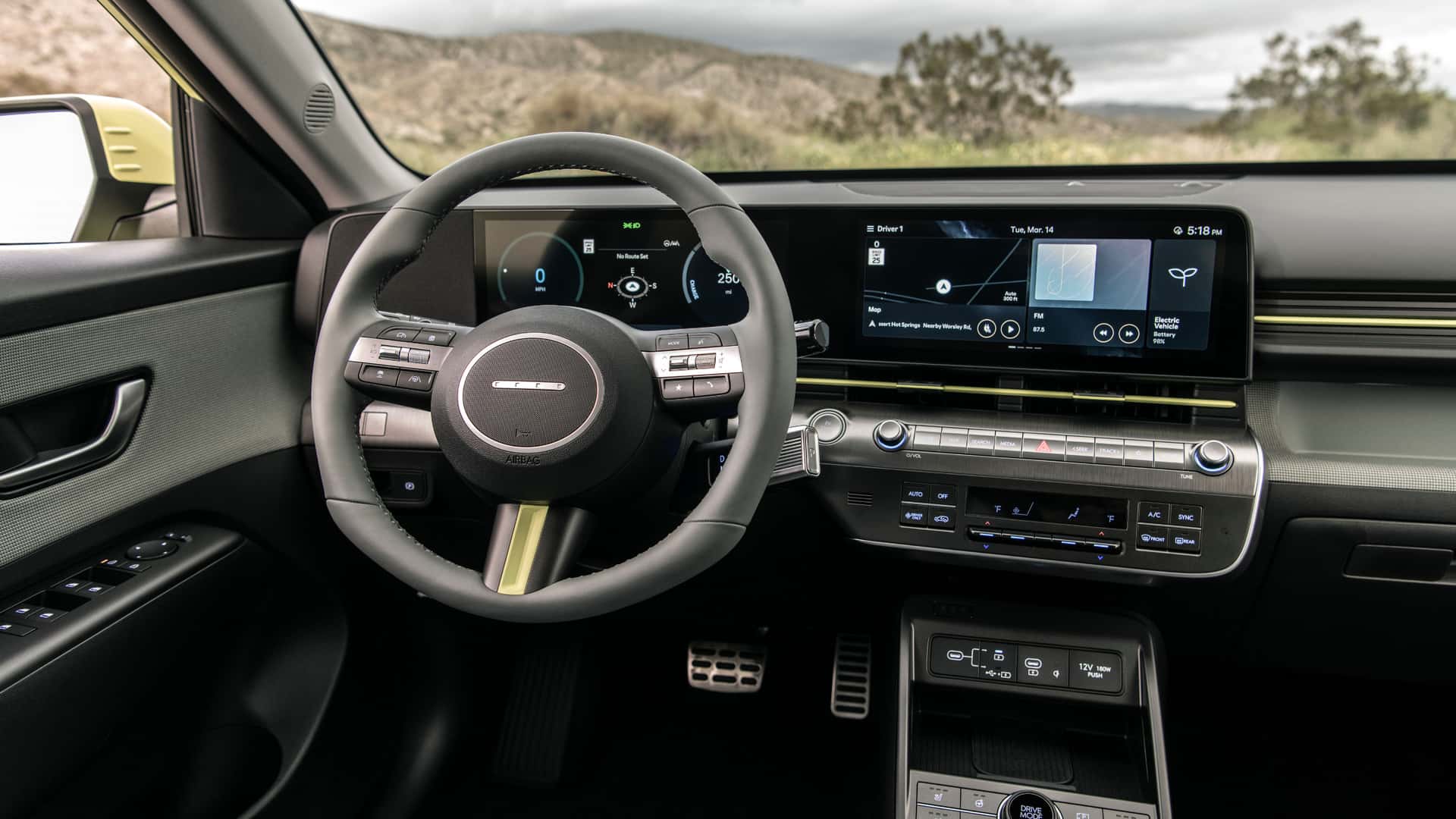 2025 Hyundai Kona Electric cockpit with steering wheel, digital gauge cluster, and center infotainment screen.