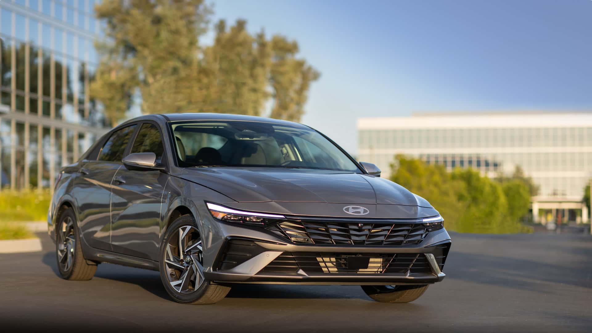 2026 Hyundai Elantra sedan parked in front of modern office buildings, front three-quarter exterior view.