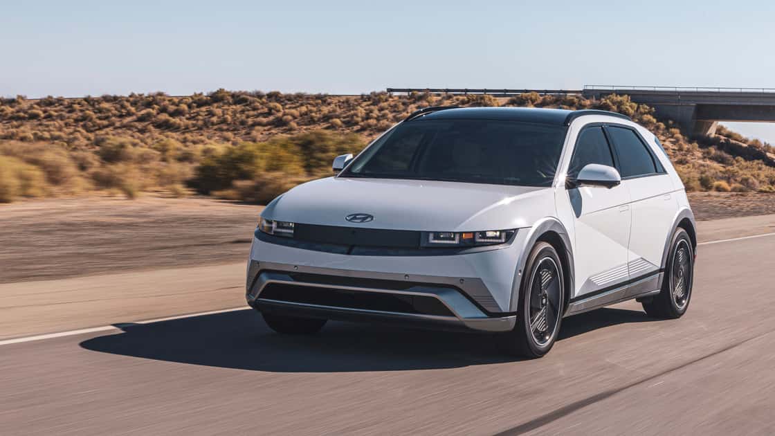2026 Hyundai IONIQ 5 driving on a desert road with a front three quarter view.