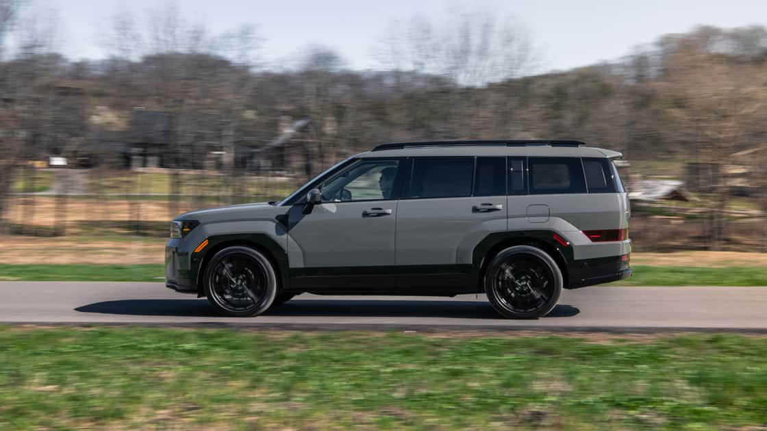 2026 Hyundai Santa Fe Hybrid driving on a rural road with a side profile view.
