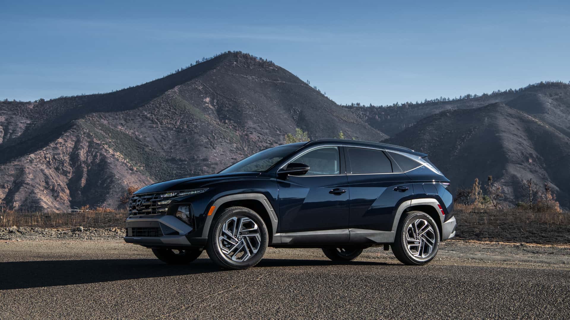 2026 Hyundai Tucson Hybrid SUV parked outdoors with rugged mountain scenery behind.