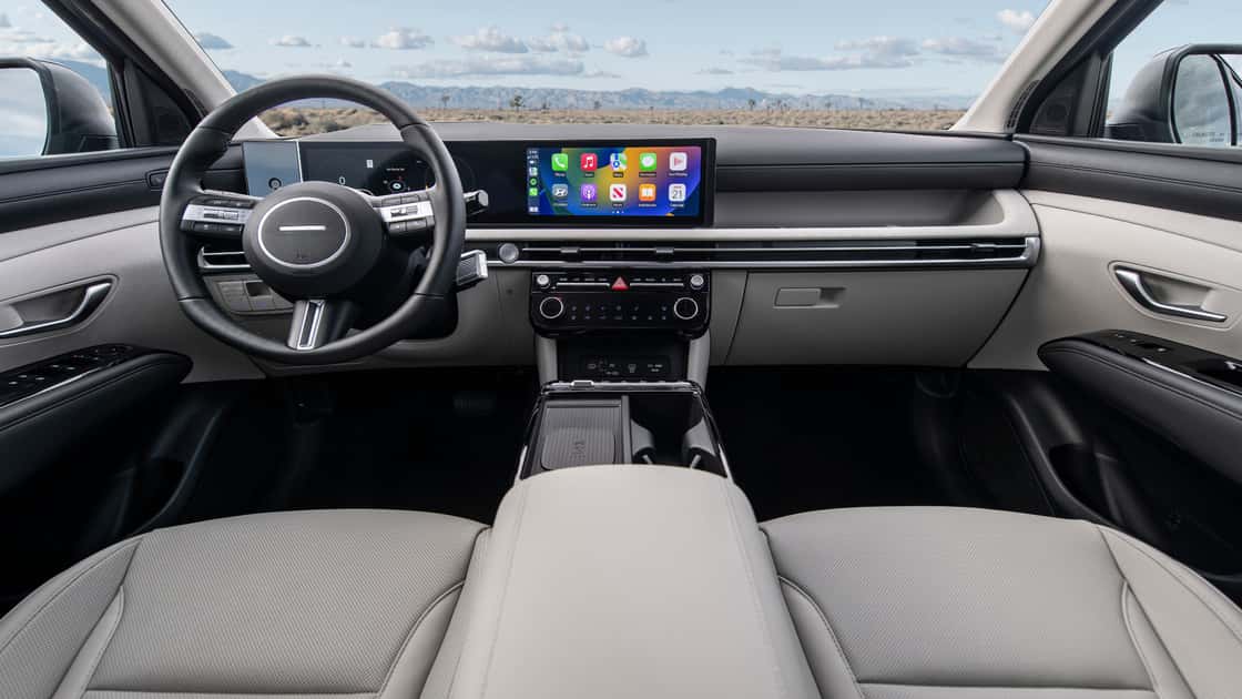 2026 Hyundai Tucson interior with wide touchscreen display, digital gauges, light cabin trim, and modern dashboard layout.