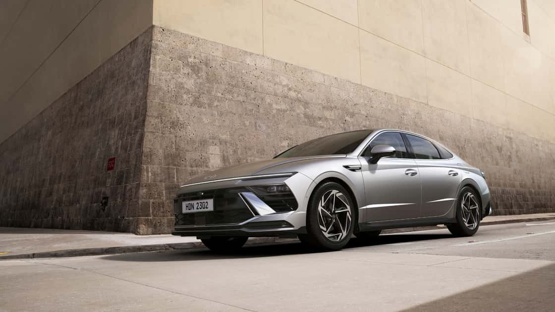 2026 Hyundai Sonata silver sedan parked near a modern city wall with sleek lighting and aerodynamic styling.