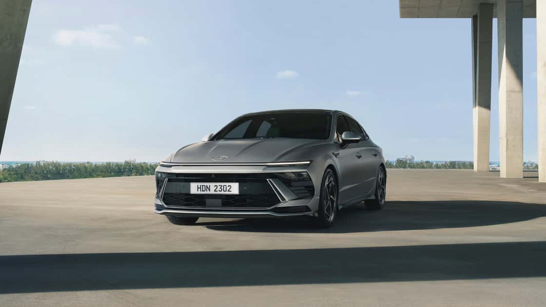 2026 Hyundai Sonata sedan parked under a modern structure with gray exterior, sharp front lighting, and sleek body styling.