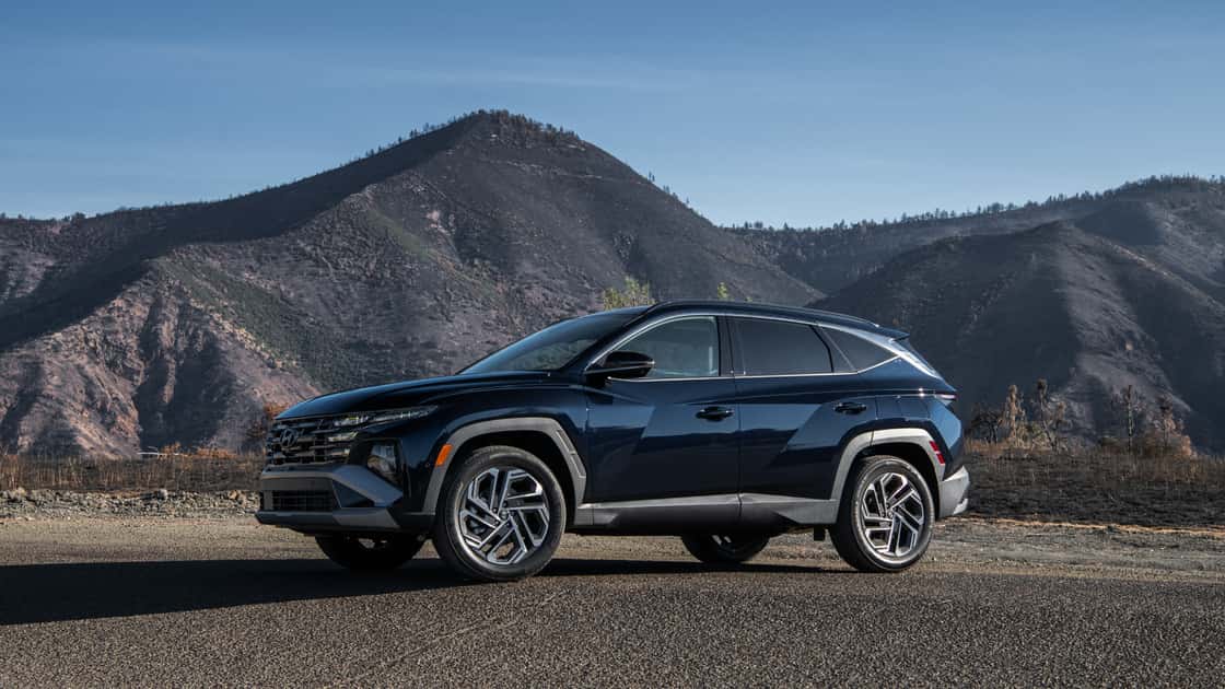 2026 Hyundai Tucson Hybrid black SUV parked near rugged mountains with sharp body lines and alloy wheels.