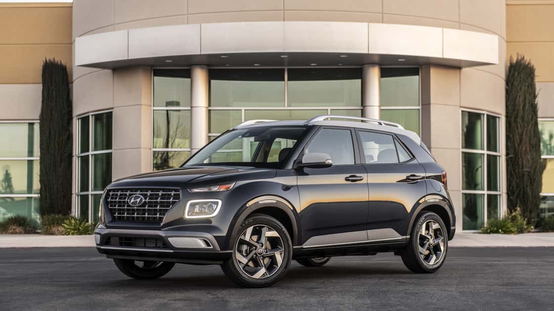 2026 Hyundai Venue in black parked outside a modern building with roof rails and compact SUV styling.