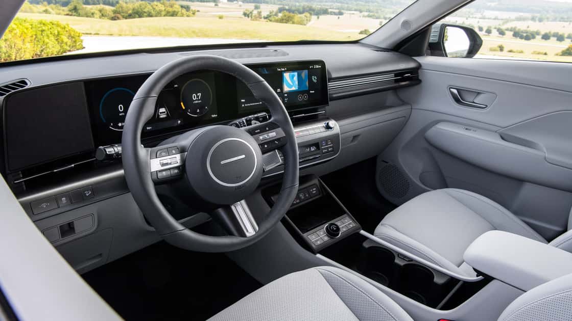2026 Hyundai Kona interior with light gray seats, digital driver display, touchscreen, and modern dashboard controls.