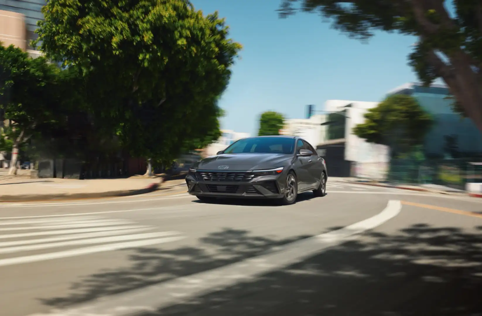 A sleek gray 2025 Hyundai Elantra Hybrid cruising through a city street.