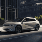 A beige 2025 Hyundai IONIQ 5 parked on a city street near modern buildings.