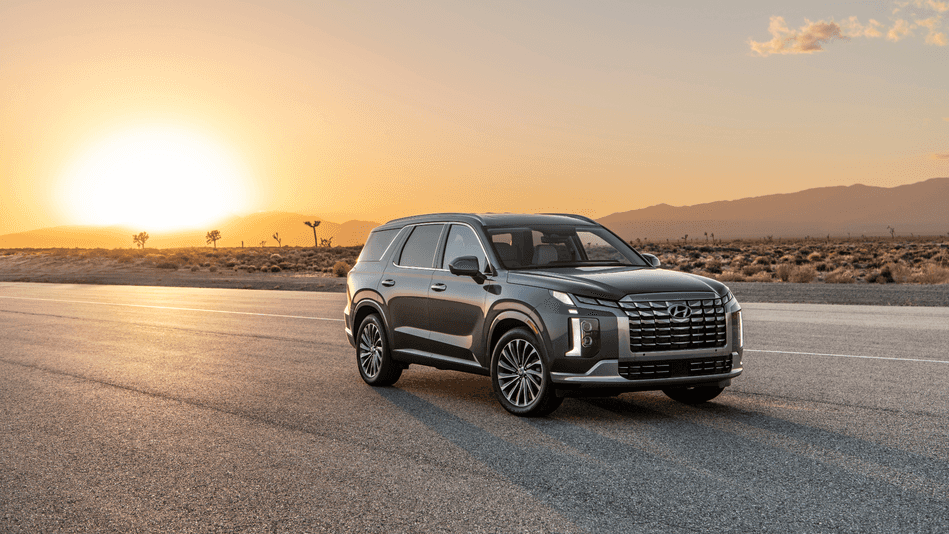 A sleek 2025 Hyundai Palisade SUV parked on an open road with a golden sunset in the background.