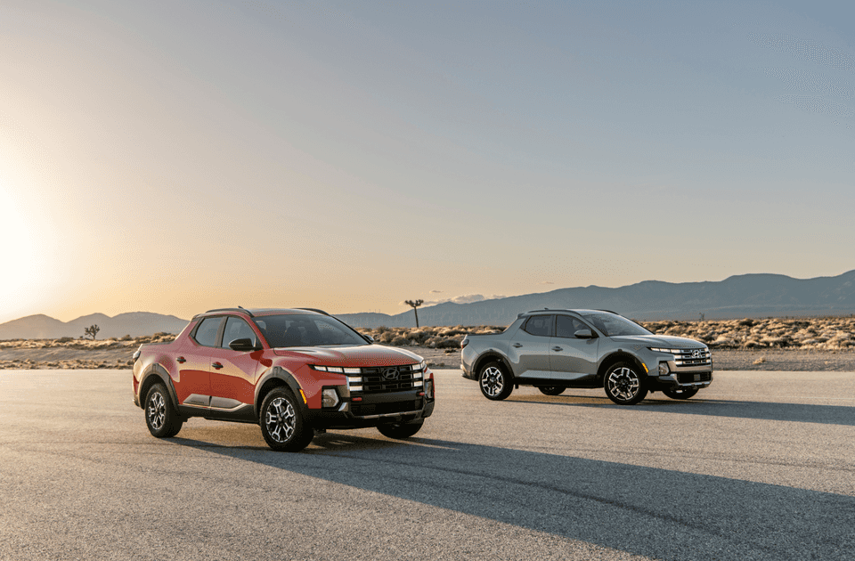 Two 2025 Hyundai Santa Cruz trucks parked in desert landscape at sunset.
