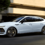 White 2025 Hyundai Sonata sedan driving in city with blurred background for motion effect.