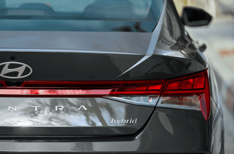 Close-up of the rear end of the 2025 Hyundai Elantra Hybrid highlighting the red LED taillight bar, Hyundai logo, and “Hybrid” badging.