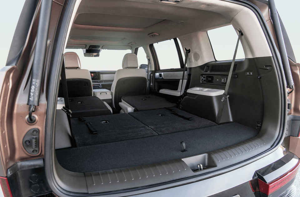 View from the rear cargo area of the 2025 Hyundai Santa Fe Hybrid with rear seats folded flat, revealing a spacious interior and expanded storage capacity.