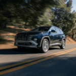 2025 Hyundai Tucson Hybrid driving on a tree-lined road with modern LED lighting and sleek design.