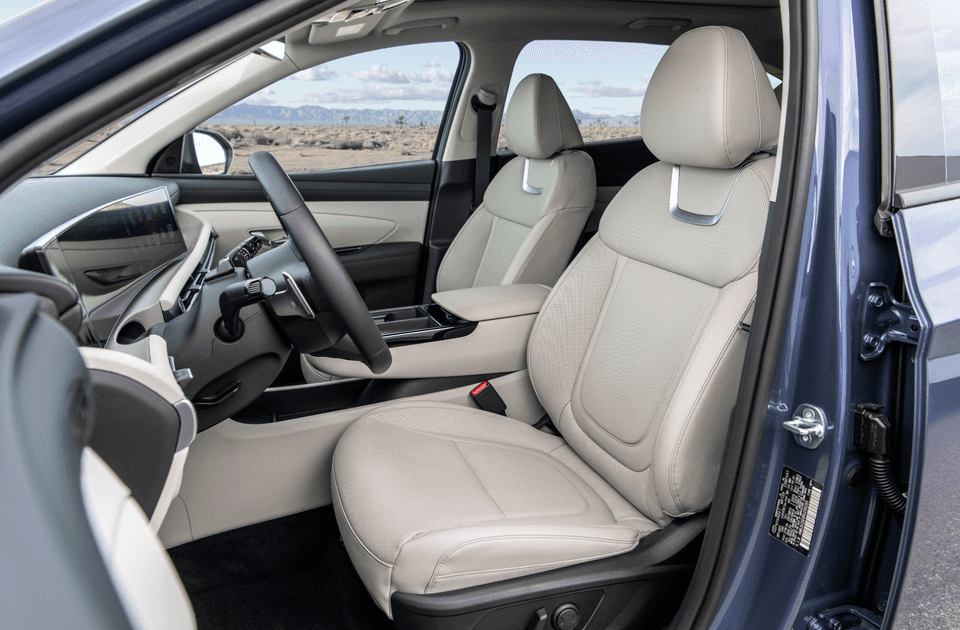 Front interior of 2025 Hyundai Tucson showing beige leather seats and digital cockpit display.