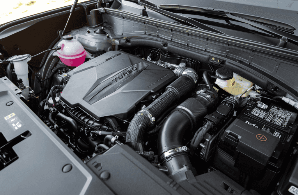 Close-up of the 2026 Hyundai Santa Fe turbocharged engine under the hood with visible components and fluid reservoirs.