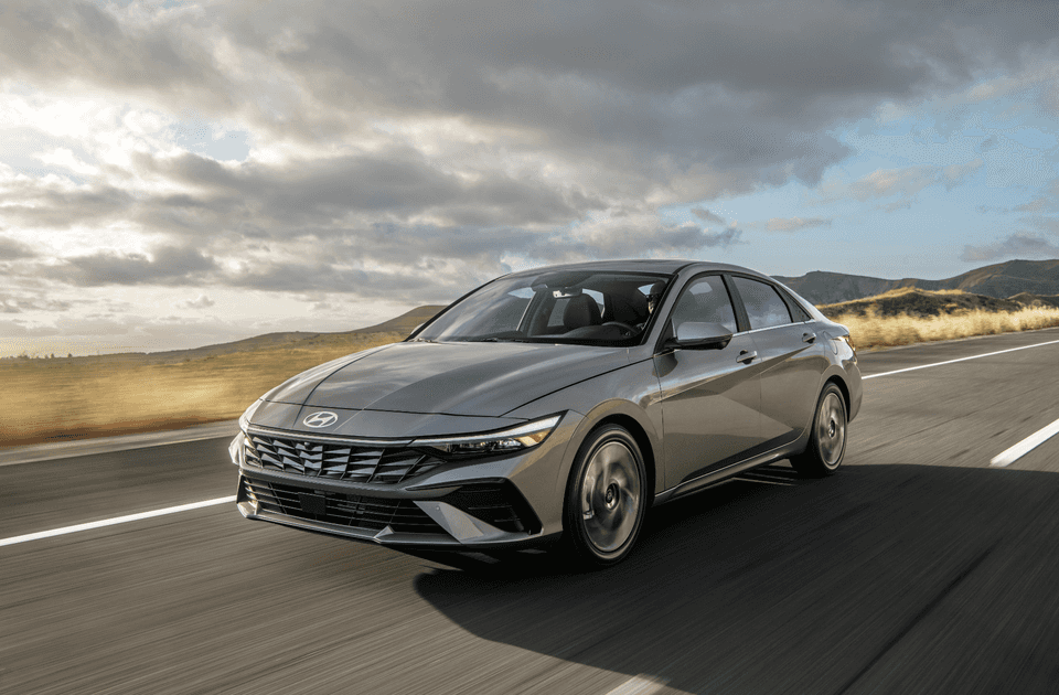 2025 Hyundai Elantra driving on open road showcasing sleek gray sedan exterior.