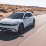 2026 Hyundai IONIQ 5 electric SUV in white driving through desert road with futuristic styling.