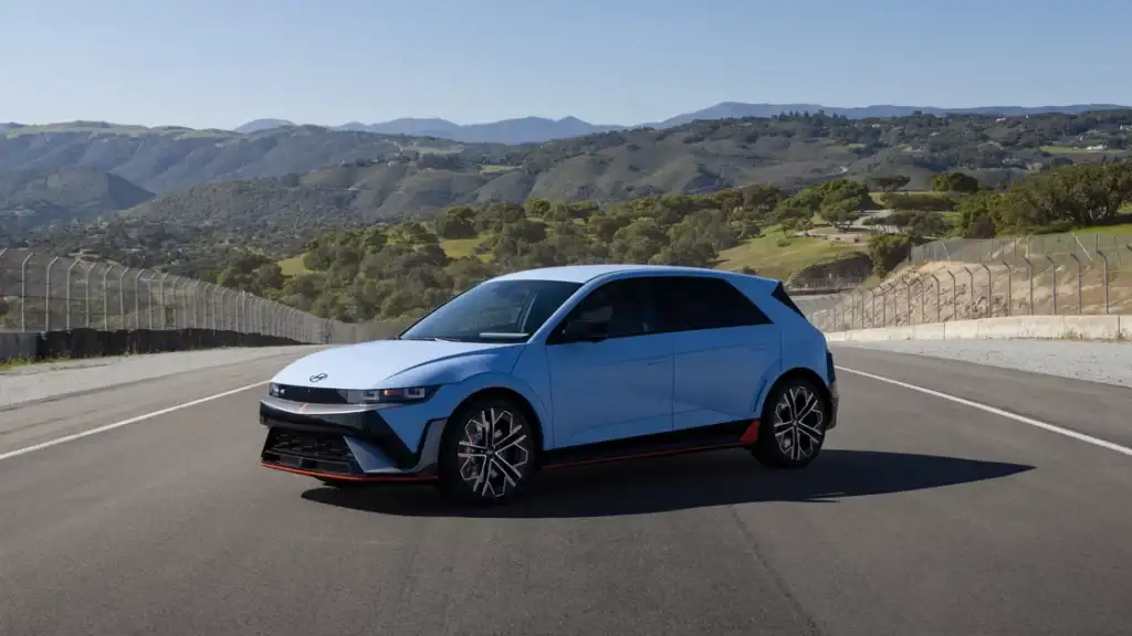 Front view of 2026 Hyundai IONIQ 5 N in blue parked on a racetrack with mountains in the background.