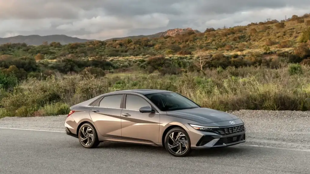 Exterior shot of the 2026 Hyundai Elantra parked roadside with scenic greenery and mountains behind.