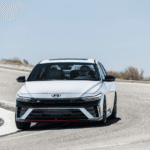 2026 Hyundai Elantra N driving on a curved road showcasing its sporty front design and performance.
