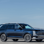 2026 Hyundai Palisade SUV shown in blue exterior, side profile on desert road with alloy wheels.