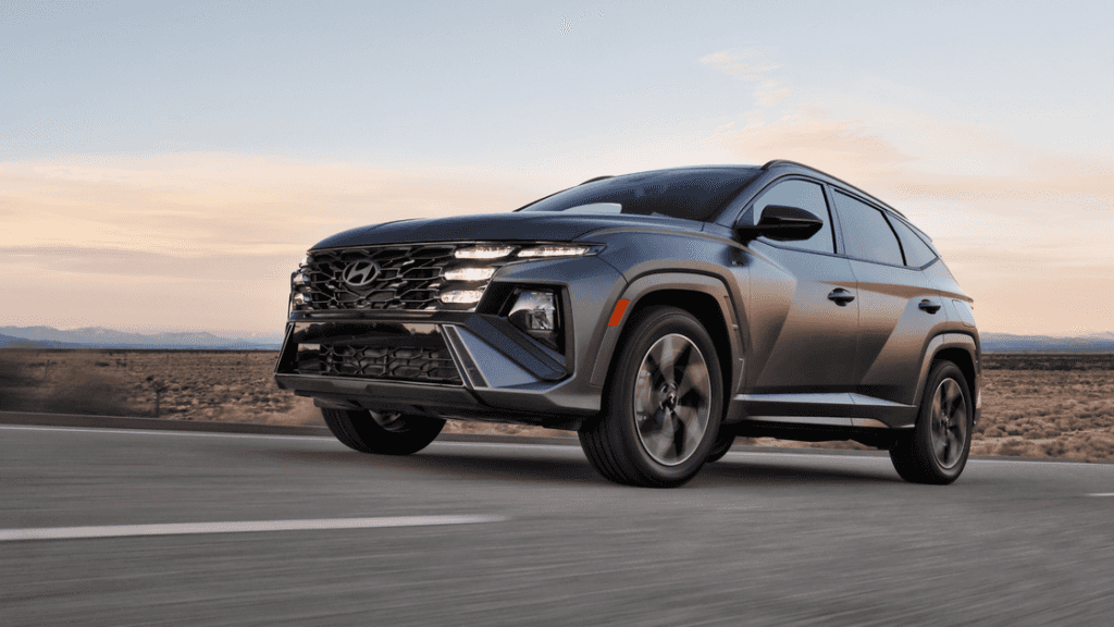 2026 Hyundai Tucson compact SUV driving on highway at dusk, front three quarter exterior view.