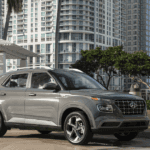 2026 Hyundai Venue subcompact SUV parked in urban setting, silver exterior with city backdrop.