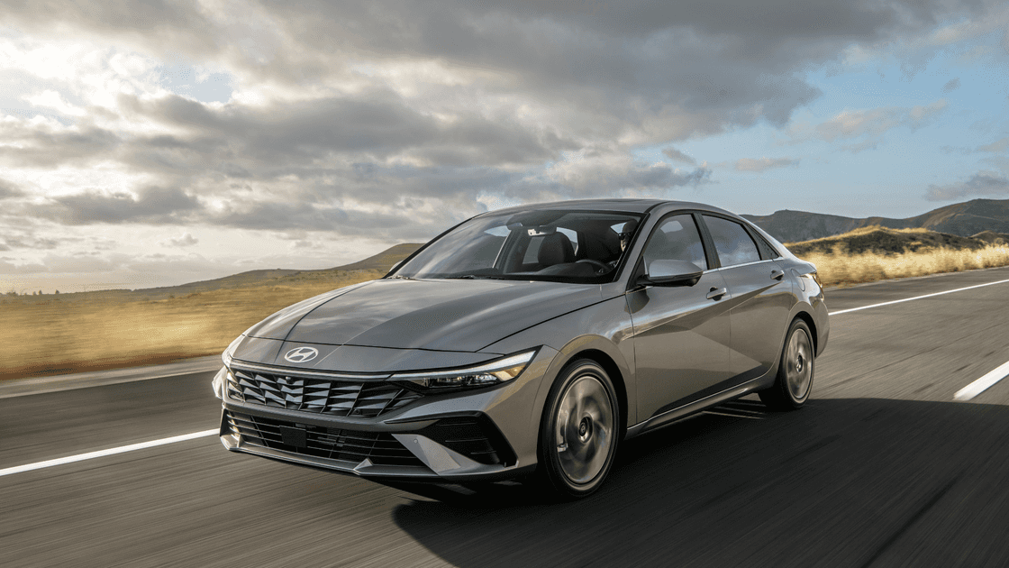 2026 Hyundai Elantra sedan driving on an open highway, front three-quarter view highlighting sleek exterior design and aerodynamic profile.
