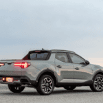 2026 Hyundai Santa Cruz compact pickup shown from rear three-quarter angle, featuring sporty bed design and modern taillights at sunset.