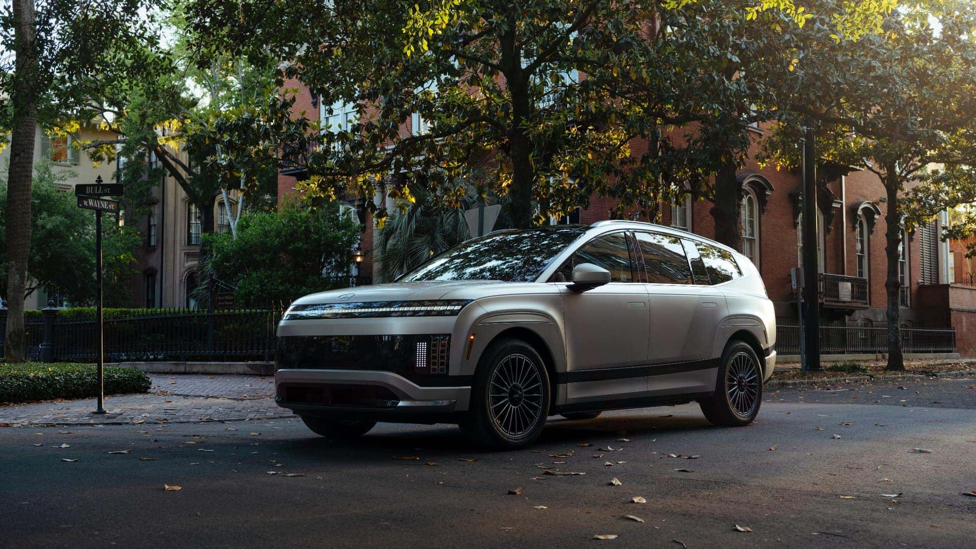 2026 Hyundai IONIQ 9 electric SUV parked on a tree-lined city street, showcasing modern exterior design and premium wheels.
