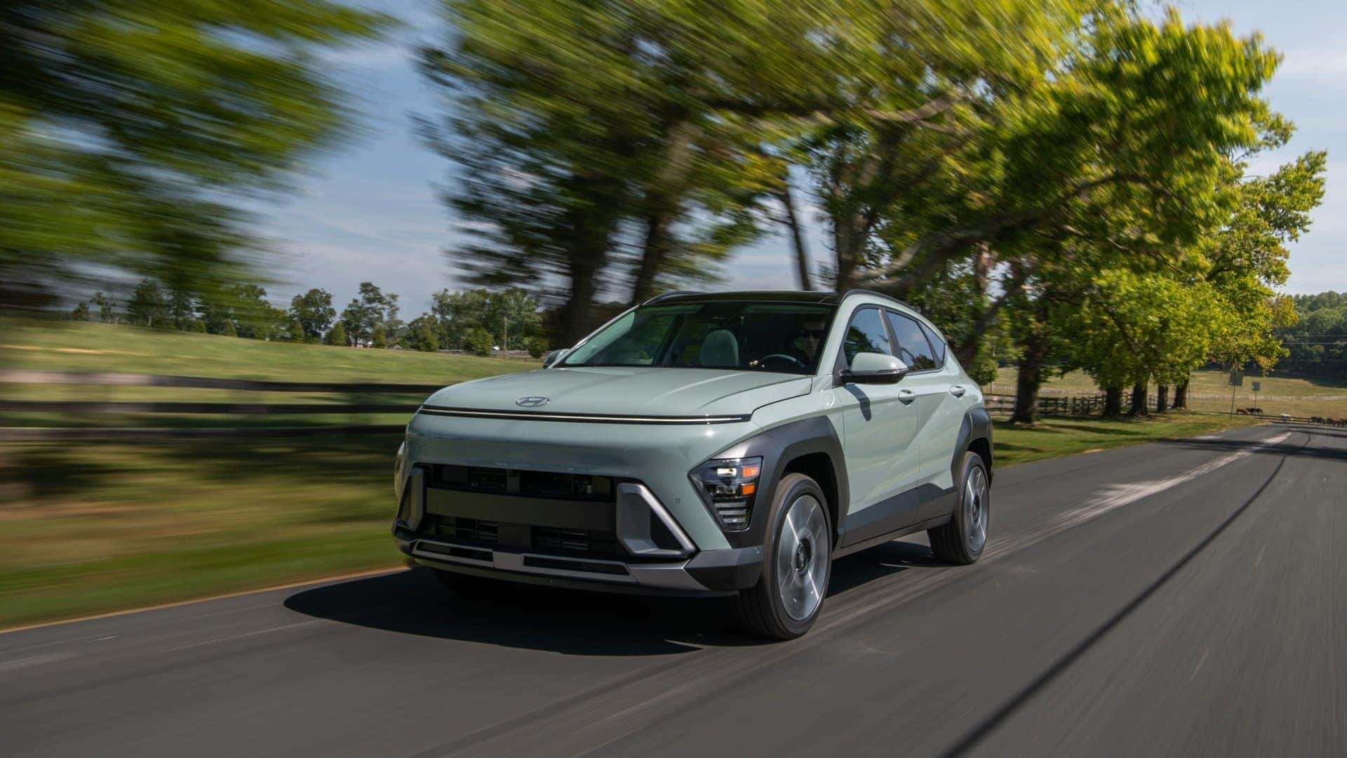 2026 Hyundai Kona compact SUV driving on a scenic road highlighting updated exterior styling and LED lighting.