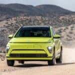 2025 Hyundai Kona Electric compact SUV in green driving on desert highway highlighting EV design and aerodynamic profile.