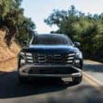 2026 Hyundai Tucson Hybrid SUV driving on scenic road featuring LED lighting signature and hybrid efficiency performance.