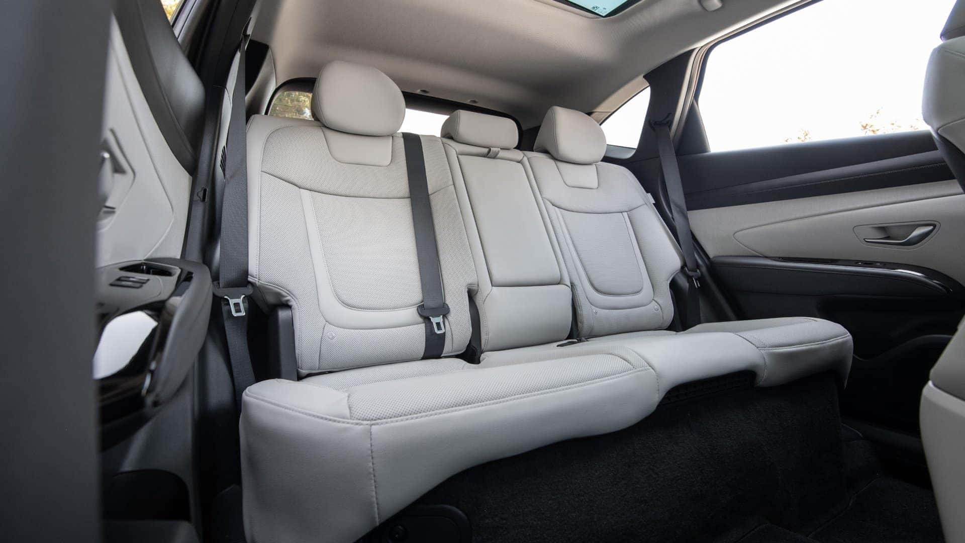 2026 Hyundai Tucson Hybrid rear passenger seats with light leather upholstery and spacious cabin.