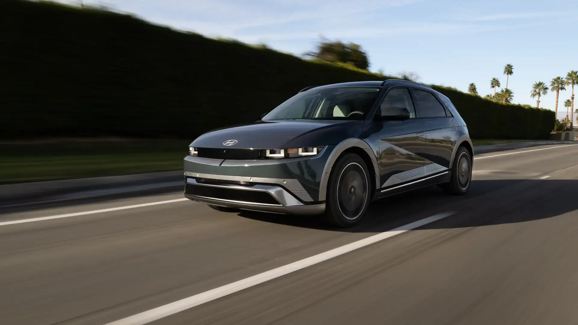 2026 Hyundai IONIQ 5 electric SUV driving on a city street in front three quarter view.