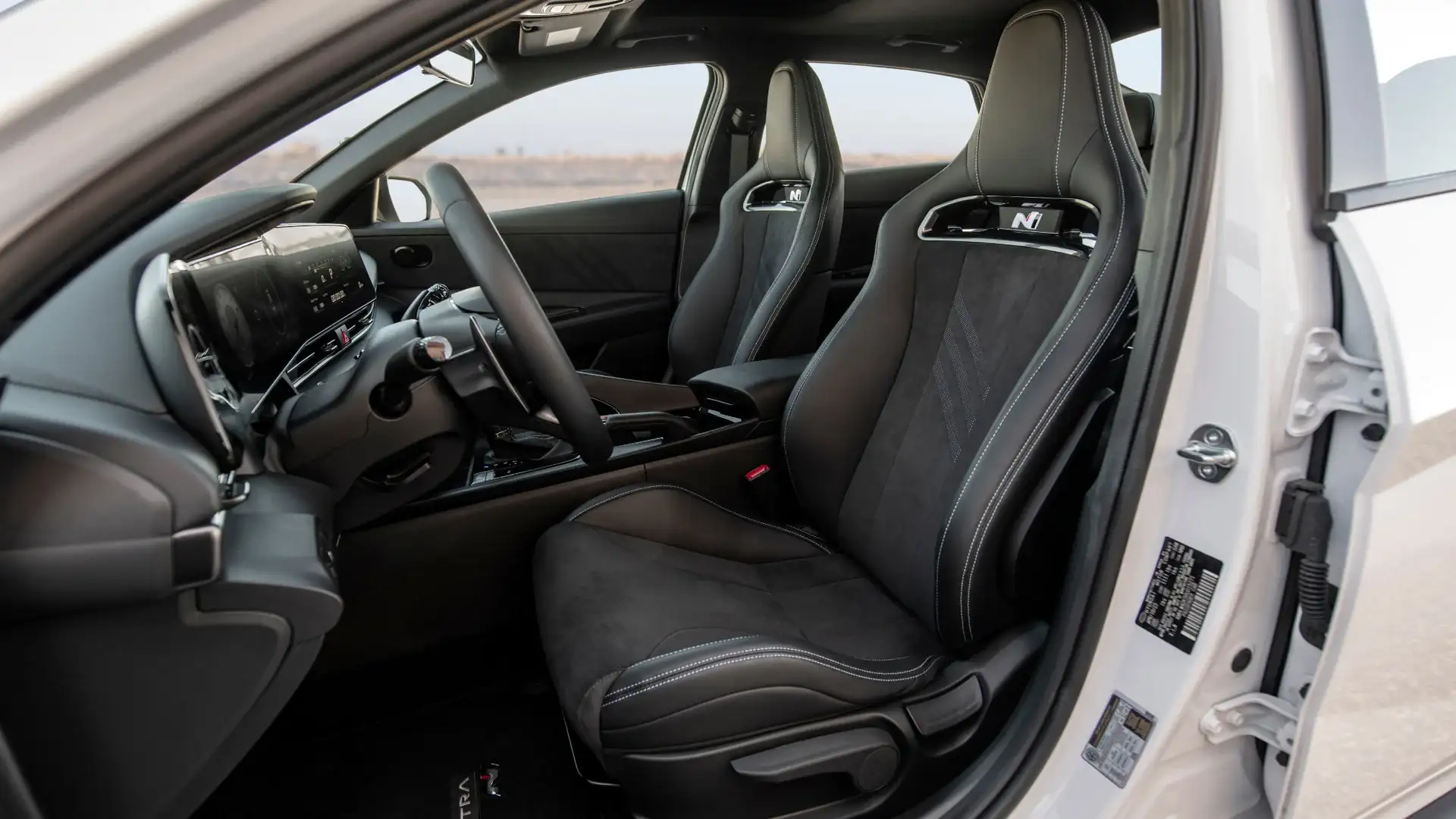 2026 Hyundai Elantra N interior side view highlighting front sport seats and center console layout.