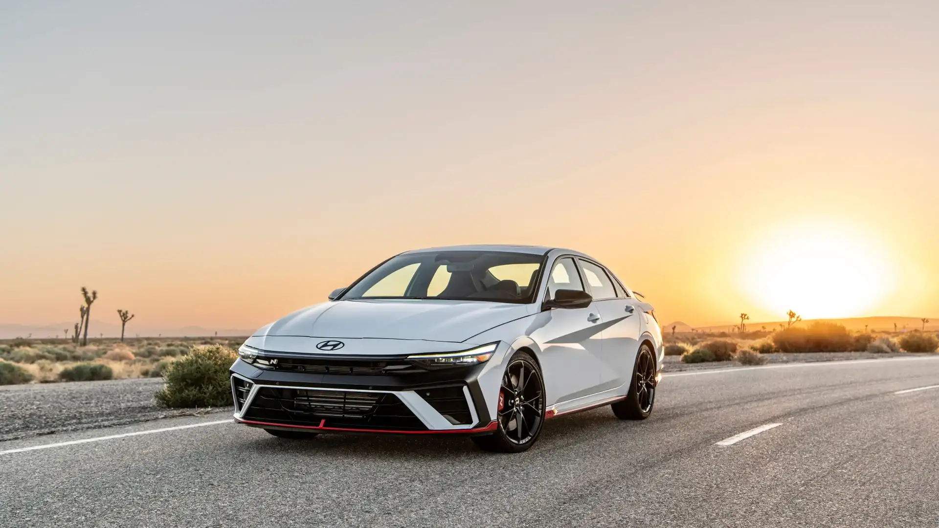 2026 Hyundai Elantra N exterior front view on desert road at sunset, showing LED headlights and sporty design.