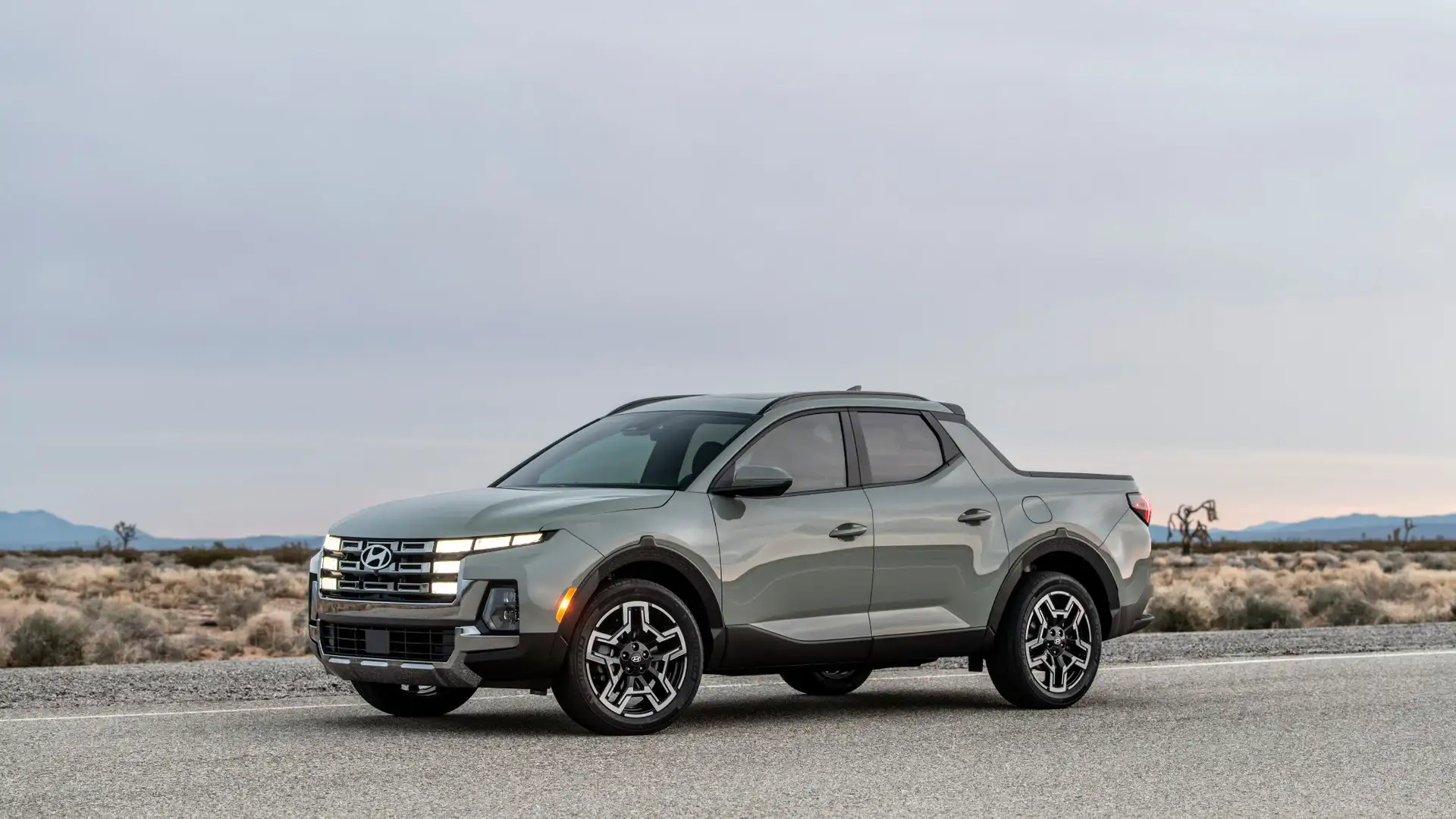 2026 Hyundai Santa Cruz gray pickup parked on desert road with LED headlights and mountain backdrop.