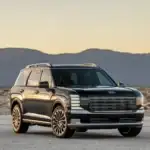 2026 Hyundai Palisade black SUV parked on desert road at sunset with mountain backdrop.