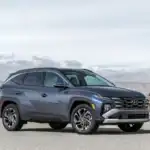 2026 Hyundai Tucson blue SUV parked in desert landscape with mountain views and bold grille.