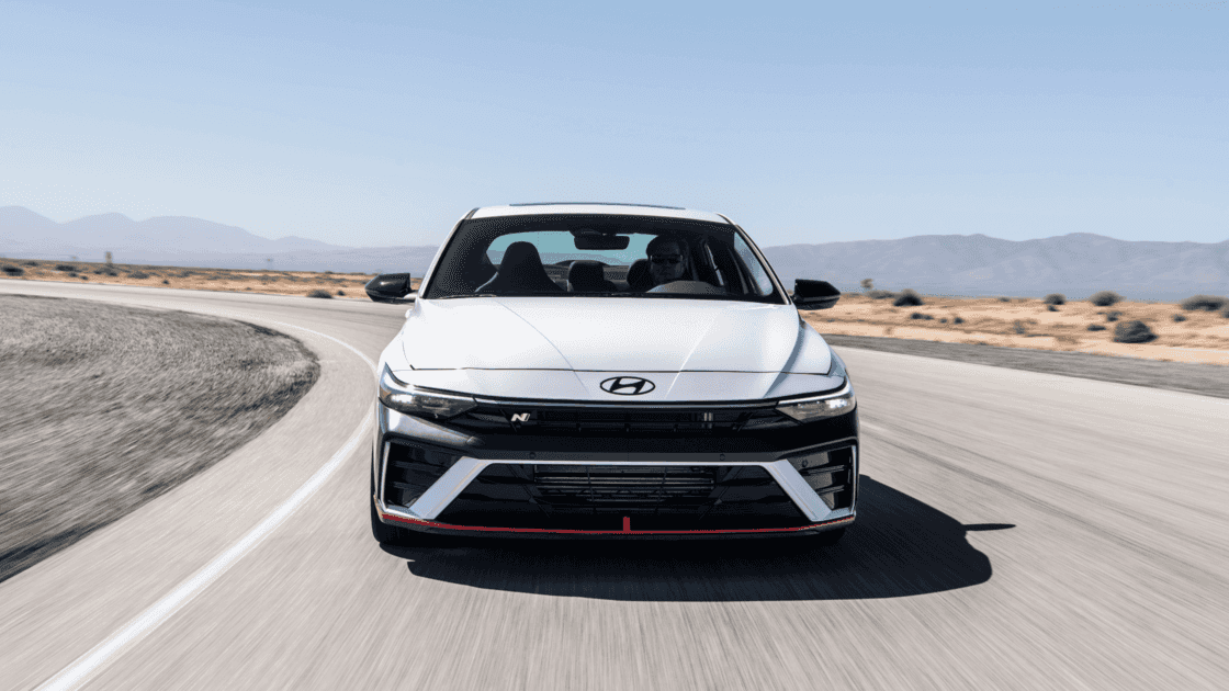 2026 Hyundai Elantra N white sport sedan driving on racetrack with front view and red trim.