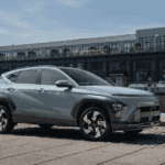 2026 Hyundai Kona gray compact SUV parked by waterfront buildings with side profile view.